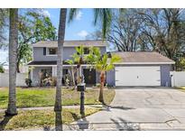 Charming two-story home features a well-maintained lawn, a two-car garage, and tasteful landscaping with palm trees at 15802 Knollview Dr, Tampa, FL 33624