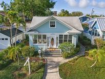 Charming light blue home featuring a landscaped front yard, sidewalk and a white picket mailbox at 210 15Th N Ave, St Petersburg, FL 33704