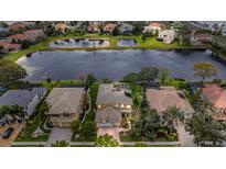 Stunning aerial view of a home near a serene lake with lush landscaping and neighboring houses at 2665 Lakebreeze N Ln, Clearwater, FL 33759
