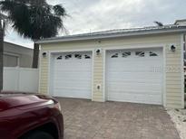Detached two car garage with white doors and brick paved driveway at 19109 Gulf Blvd, Indian Shores, FL 33785