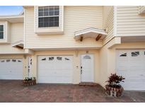 Charming townhome exterior featuring a one-car garage, brick driveway, and inviting entrance at 19651 Gulf Blvd # A6, Indian Shores, FL 33785