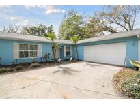 Charming light blue single story home, lush landscaping, and white two car garage at 22002 Darley Pl, Land O Lakes, FL 34639