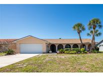 Charming single-story home with arched entryway, two-car garage, and mature palm trees at 736 Flamingo Dr, Apollo Beach, FL 33572