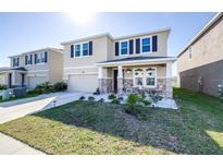 Charming two-story home featuring stone accents, a covered front porch, and a well-manicured lawn at 9119 Forge Breeze Loop, Wesley Chapel, FL 33545