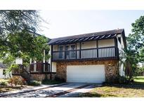 Two-story home showcasing a stone-clad garage, upper-level balcony, and charming curb appeal at 130 80Th Ne Ave, St Petersburg, FL 33702