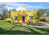 Charming yellow home with red tile entry, fresh landscaping, and a cozy front bench at 2310 13Th W Ave, Bradenton, FL 34205