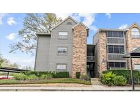 Exterior view of a three-story condo building featuring wood siding, brick accents, and well-maintained landscaping at 2500 Winding Creek Blvd # E302, Clearwater, FL 33761