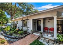 Charming home featuring a landscaped front yard and a welcoming covered porch with red chairs at 3026 51St S St, Gulfport, FL 33707