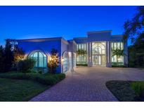 Elegant home featuring an arched entryway, grand windows, a circular driveway, and lush landscaping at 110 Harbor View Ln, Belleair Bluffs, FL 33770