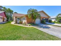 Charming home with a two-car garage, brick accents and mature landscaping with palm trees at 3210 Mcmath Dr, Palm Harbor, FL 34684