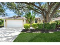 Charming home exterior with a well-maintained lawn, mature trees, and a two-car garage at 5141 Sunnydale W Cir, Sarasota, FL 34233