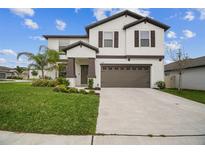 Charming two-story home with well-manicured lawn and a two-car garage, offering curb appeal and convenience at 6241 Spider Lily Way, New Port Richey, FL 34653