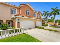 Charming two-story townhome boasts a white garage door and decorative fence, surrounded by lush landscaping at 6345 Vista Verde E Dr, Gulfport, FL 33707