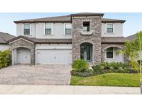 Charming two-story home featuring stone accents, a brick driveway, and manicured landscaping at 13176 Twin Bridges Dr, Riverview, FL 33579