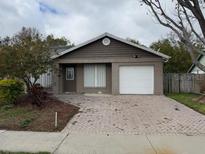 Cozy one-story home featuring a quaint front yard and a brick-paved driveway leading to an attached garage at 1525 Kestrel Way, Brandon, FL 33511