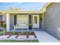 Charming front porch with white bench seating, decorative pillows, and well-maintained landscaping at 1842 Oklahoma Ne Ave, St Petersburg, FL 33703