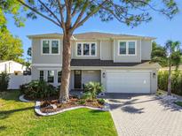 Charming two-story home featuring a well-manicured lawn, brick driveway, and lush landscaping at 4012 W Morrison Ave, Tampa, FL 33629