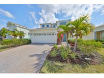 Beautiful two-story home featuring a two-car garage, lovely landscaping, and vibrant palm trees at 5232 Wishing Arch Dr, Apollo Beach, FL 33572
