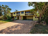 Two-story home with a gravel driveway, green lawn, covered carport, and an American flag at 724 69Th S Ave, St Petersburg, FL 33705
