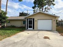 Charming single-story home with a well-maintained lawn, attached garage and screened entryway at 7406 Coventry Dr, Port Richey, FL 34668