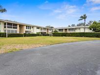 Property featuring a lush green lawn, mature trees, and multiple building sections with clean architectural lines at 8303 Bardmoor Blvd # 105, Seminole, FL 33777