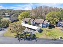Aerial view of condo building with carports, green space, and a partial view of a lake on a sunny day at 12135 Environmental Dr # 2, New Port Richey, FL 34654