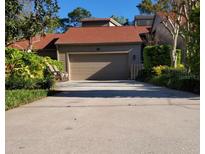 Charming home featuring a two-car garage and beautifully landscaped front yard and walkway leading up to the house at 20 Woodridge Cir, Oldsmar, FL 34677