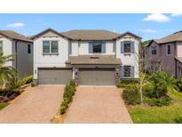 Charming two-story townhouse featuring a brick-paved driveway and a two-car garage at 4896 San Martino Dr, Wesley Chapel, FL 33543