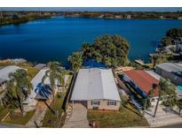 Waterfront home with a long driveway and lush landscaping in a serene lakeside setting at 826 Paradise Blvd, Tarpon Springs, FL 34689