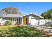 Charming single-story home features a well-manicured lawn and a bright yellow front door, enhancing its curb appeal at 3059 Hickory Dr, Largo, FL 33770