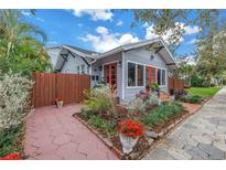 Charming home featuring vibrant landscaping, a red brick walkway and a cheerful, red front door at 436 12Th Ne Ave, St Petersburg, FL 33701