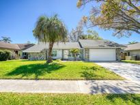 Charming home featuring stone accents, a well-manicured lawn, and a two-car garage at 2988 Pinewood Run, Palm Harbor, FL 34684