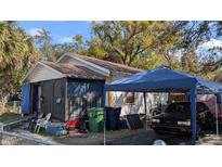 Exterior view of a home with an enclosed porch and a vehicle parked under a blue carport at 3203 N 31St St, Tampa, FL 33605