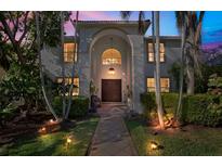 Elegant two-story home with a grand arched entrance, lush landscaping, and warm exterior lighting at 355 21St Ne Ave, St Petersburg, FL 33704
