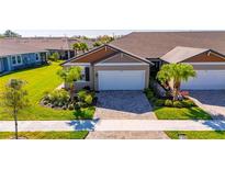 Charming single-story home with a well-manicured lawn, lush landscaping, and a two-car garage at 3753 Maxwell Park Dr, Sun City Center, FL 33573