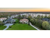 Stunning aerial view of a lakeside home with lush green lawn, mature trees, and a beautiful water view at 5914 Fitzgerald Rd, Odessa, FL 33556