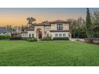 Charming two-story home with a well-manicured lawn, arched entry, and lush landscaping at 5914 Fitzgerald Rd, Odessa, FL 33556