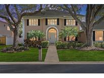 Charming two-story home featuring lush landscaping, mature trees, and a welcoming front entrance at 902 Marco Ne Dr, St Petersburg, FL 33702