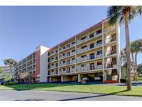 Spacious condo building featuring multiple balconies, covered parking, and lush landscaping at 9433 Harbor Greens Way # 405, Seminole, FL 33776