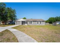 Charming single-story home featuring a screened-in porch, attached garage, and a well-maintained front yard at 1225 Harvest Home Ct, Ruskin, FL 33570