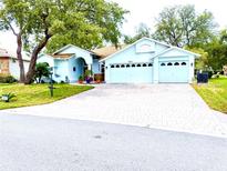 Charming single-story home with a three-car garage and a brick-paved driveway at 2069 Overbrook Ln, Spring Hill, FL 34606