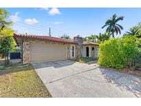 Charming single-story home featuring a tiled roof, stone accents, and attached garage with a concrete driveway at 360 22Nd Ne Ave, St Petersburg, FL 33704