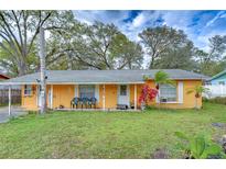 Charming yellow home with inviting front porch and well-maintained lawn at 40111 Pretty Redbird Rd, Zephyrhills, FL 33540