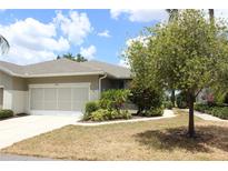 Charming single-story home with a well-manicured lawn and beautiful landscaping, including colorful shrubs and a mature shade tree at 2129 Acadia Greens Dr, Sun City Center, FL 33573