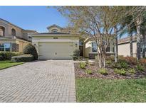 Charming home with a brick driveway, a two-car garage, and manicured landscaping at 30280 Southernwood Ct, Wesley Chapel, FL 33543