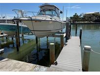 View of boat sitting on a lift at the dock, with water reflections at 329 Medallion Blvd # C, Madeira Beach, FL 33708