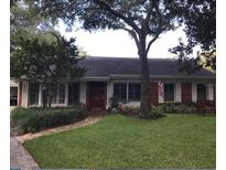Charming single-story brick home with a lush green lawn and mature trees providing ample shade at 5110 W Evelyn Dr, Tampa, FL 33609