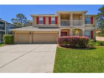 Charming two-story home features a spacious three-car garage, red shutters and a well-manicured lawn at 7309 Night Heron Dr, Land O Lakes, FL 34637