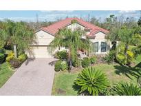 Beautiful single-story home boasts lush landscaping, a red tile roof, and a paver driveway at 8057 Rio Bella Pl, Bradenton, FL 34201