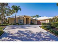 Stunning single-Gathering home with a beautiful brick driveway, lush landscaping, and a well-manicured lawn at 10411 Cory Lake Dr, Tampa, FL 33647